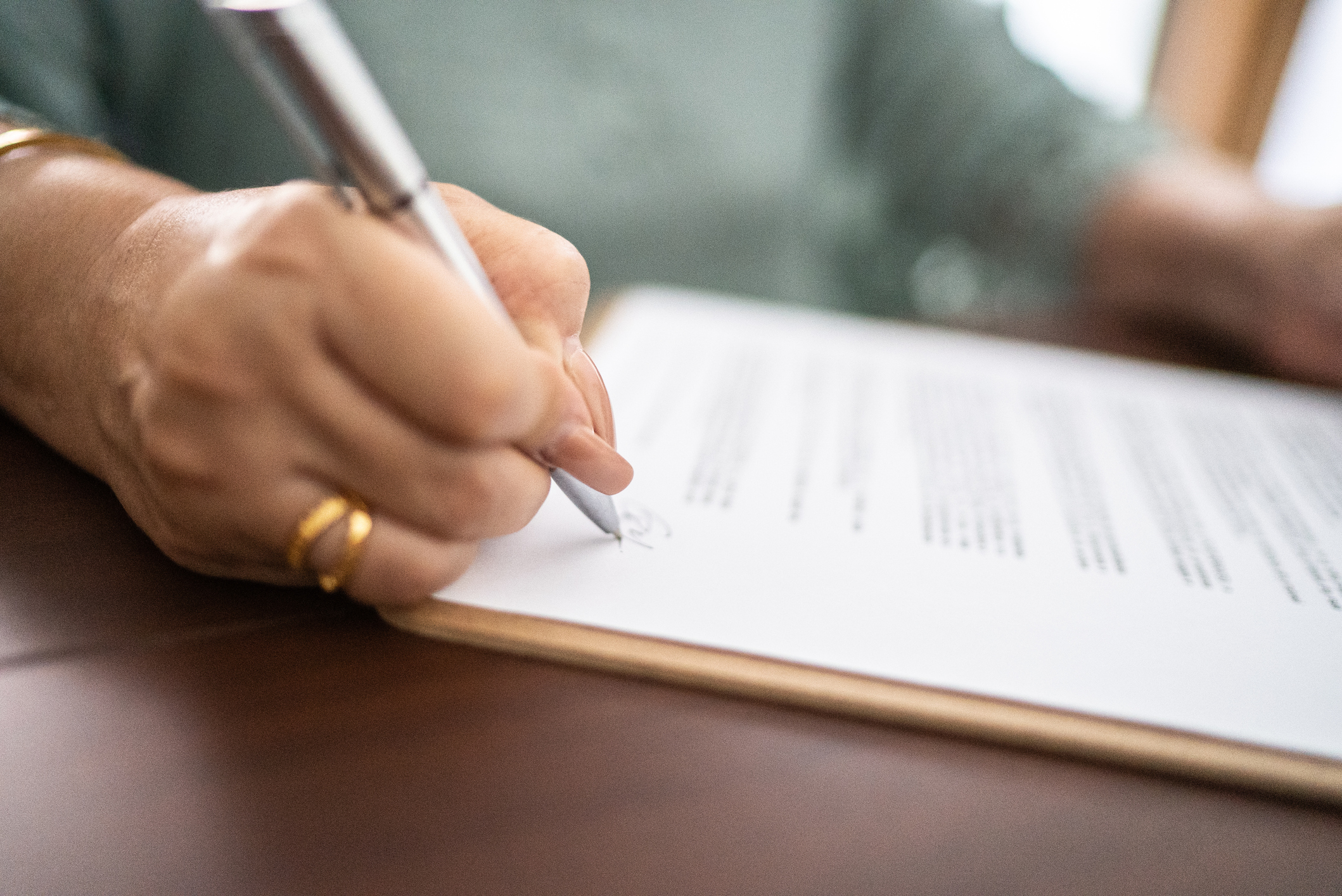 Hand with pen writing on paper on a desk